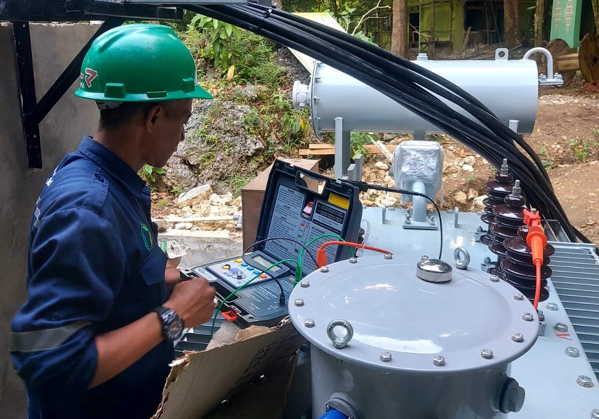 Technician performing electrical testing on transformer during commissioning