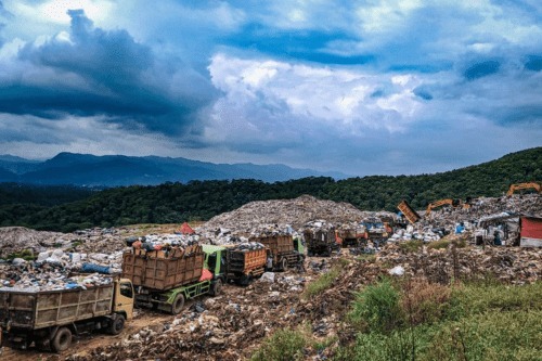 Active municipal solid waste landfill with dump trucks and excavator